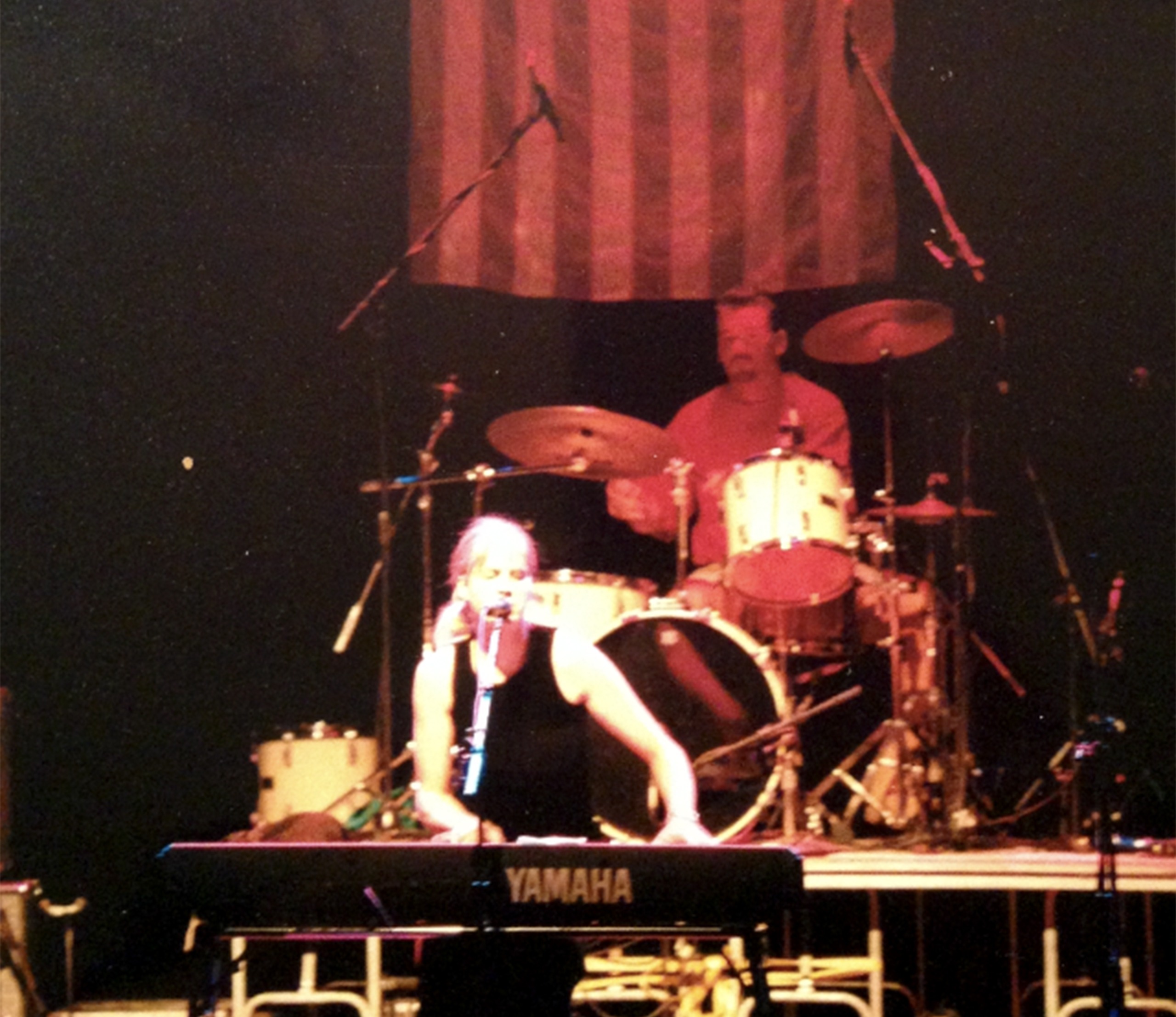 On stage, a woman performs on a keyboard, with an American flag